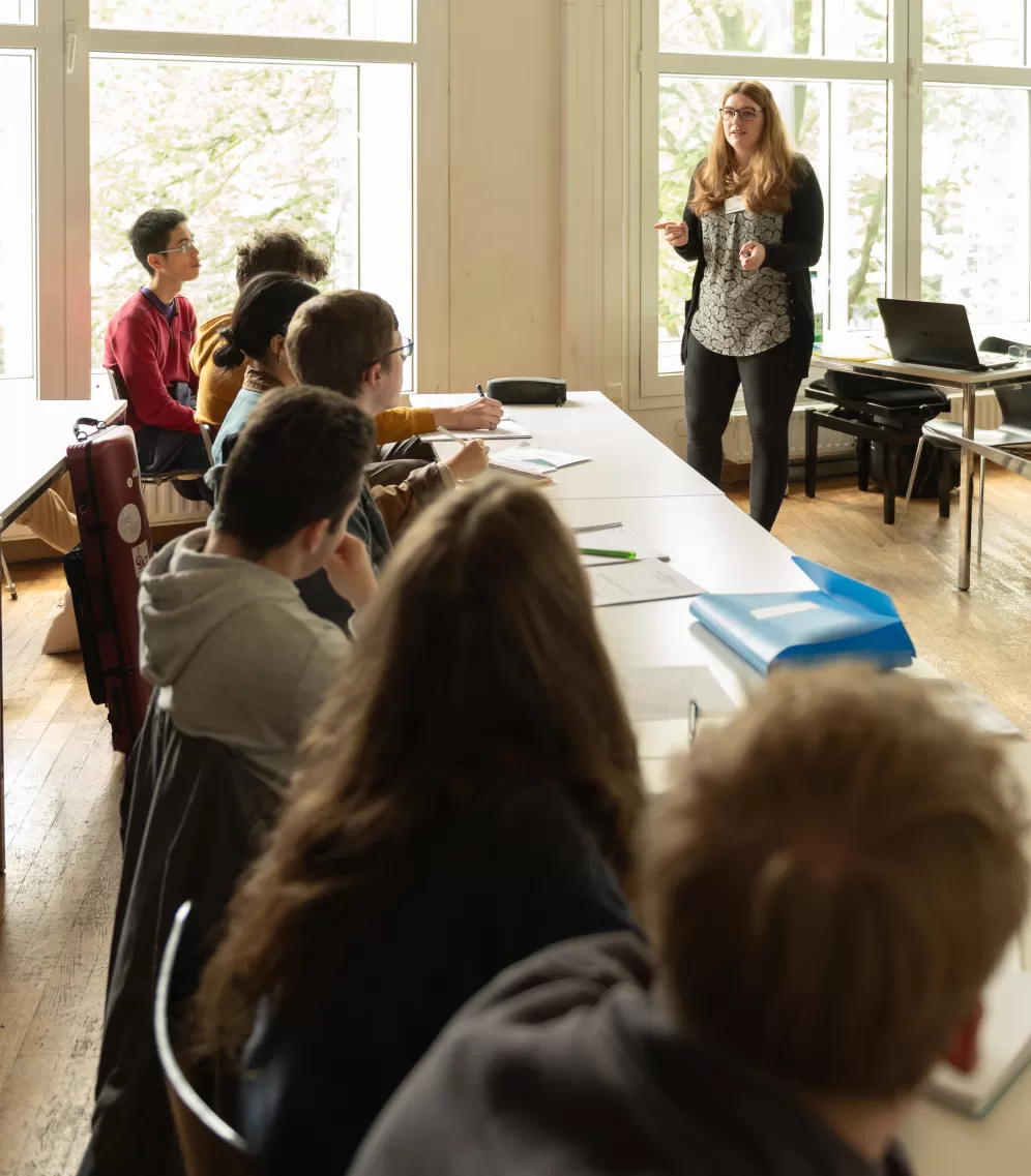 Eine Dozentin erklärt einer Gruppe von Teilnehmenden des Infotags Lehramt Musik etwas.