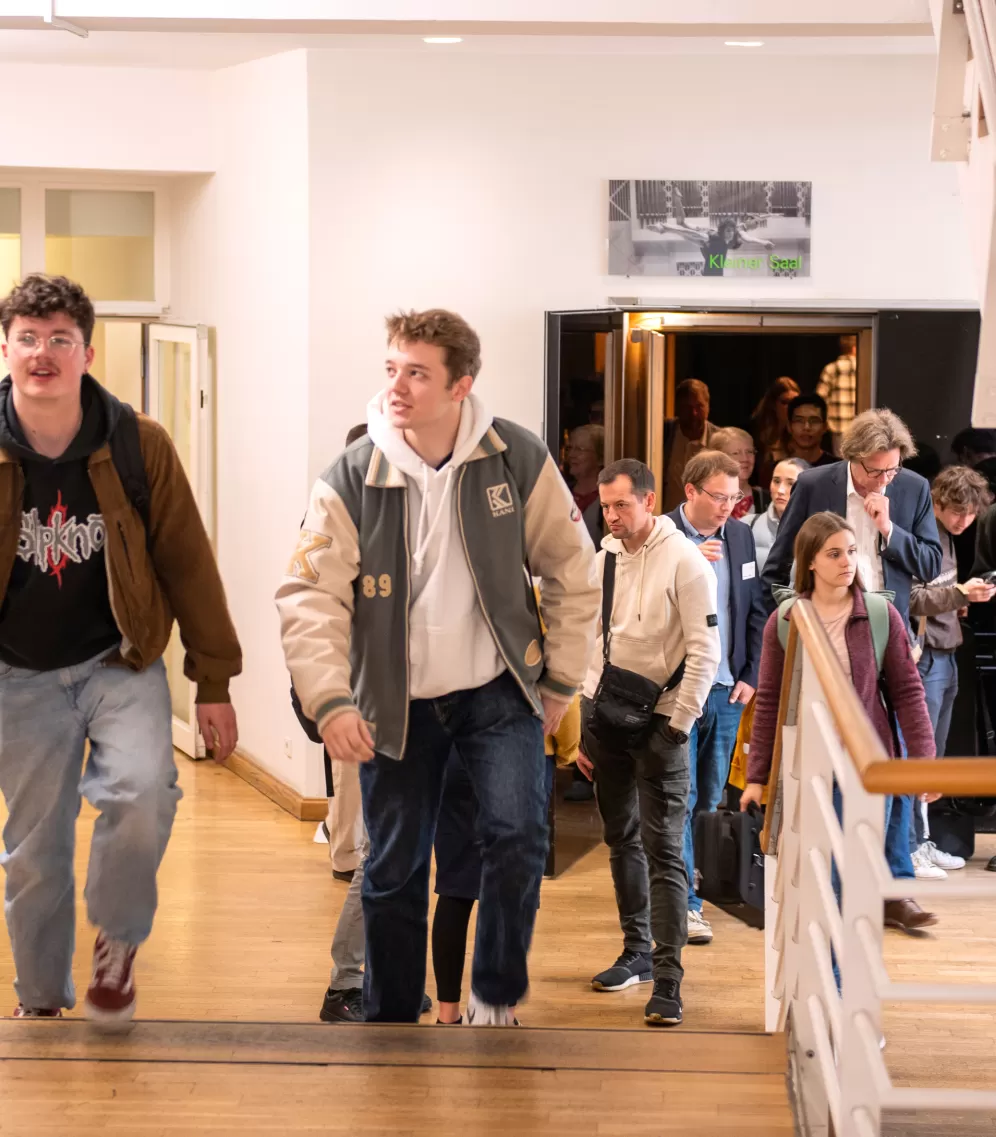 Eine Gruppe von Schüler*innen läuft beim Infotag Lehramt durch das Foyer und Treppenhaus der HfMDK Frankfurt.