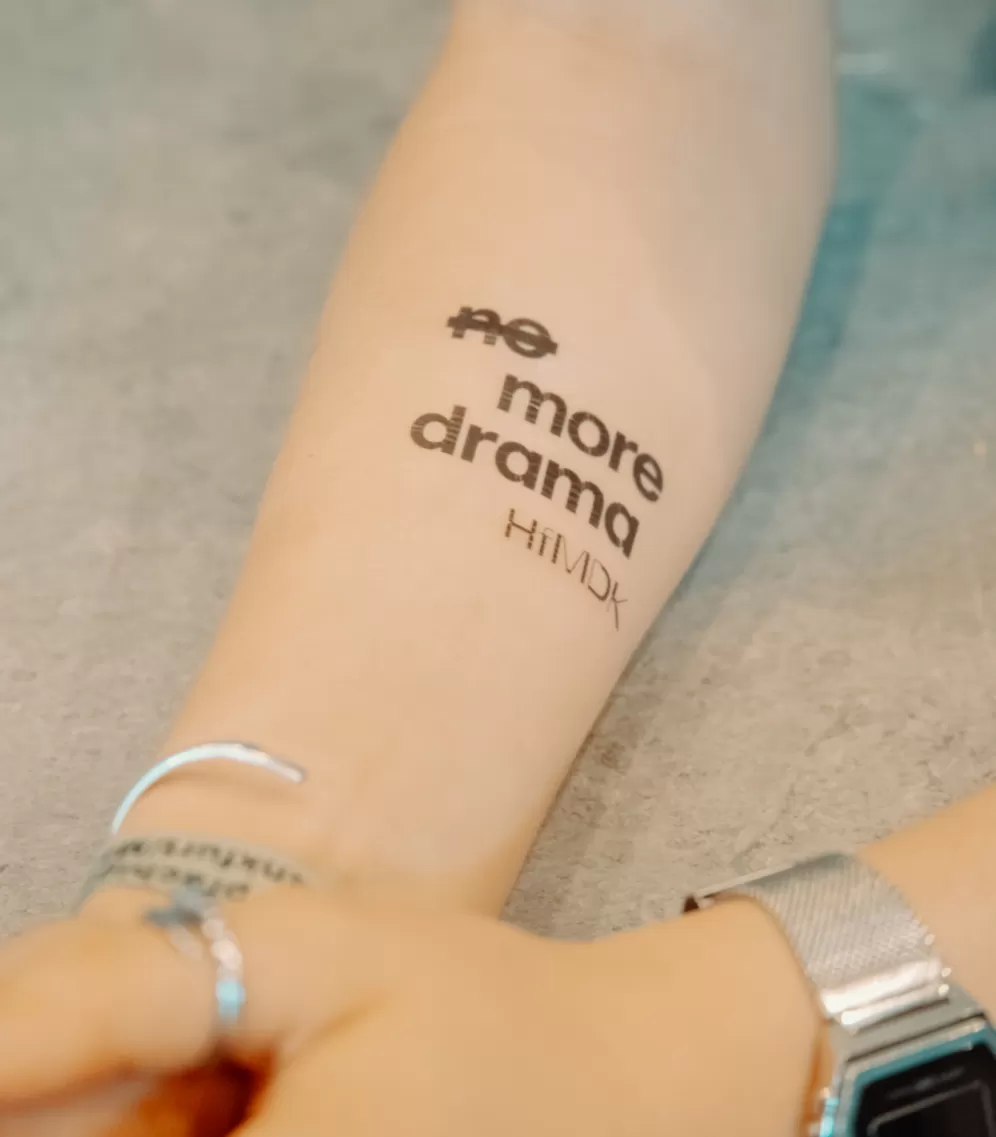Nahaufnahme des temporären "No more drama" Tattoos auf dem Unterarm einer Person.