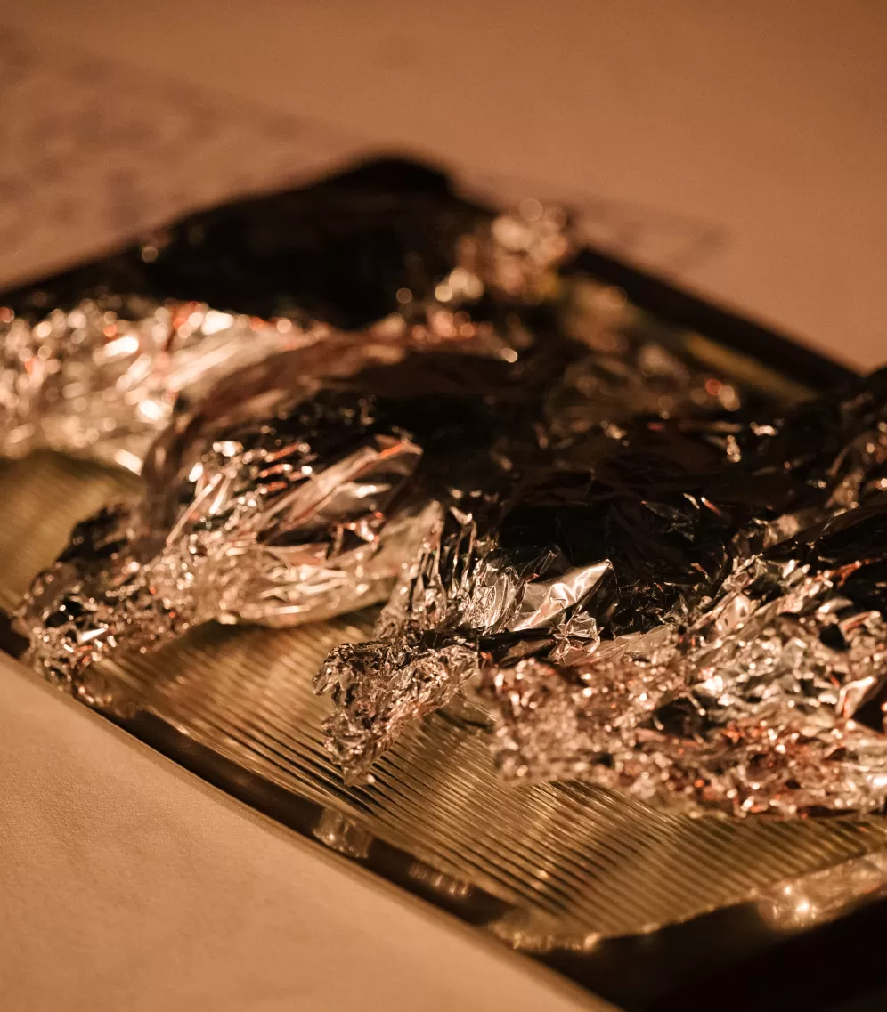 In Alufolie verpacktes Essen auf einem silbernen Tablett.