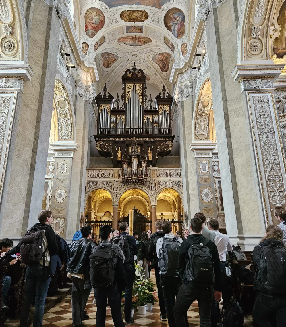 Stift Klosterneuburg: Blick von Altarraum auf Orgel, Reisegruppe steht im Mittelgang und hört den Erklärungen des Stiftsorganisten zu