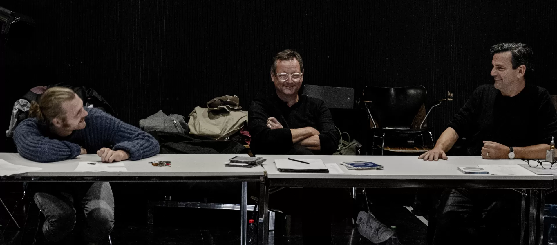 Schauspieler Matthias Brandt und Regisseur Christian Petzold sitzen am Tisch mit einem Schauspielstudenten.