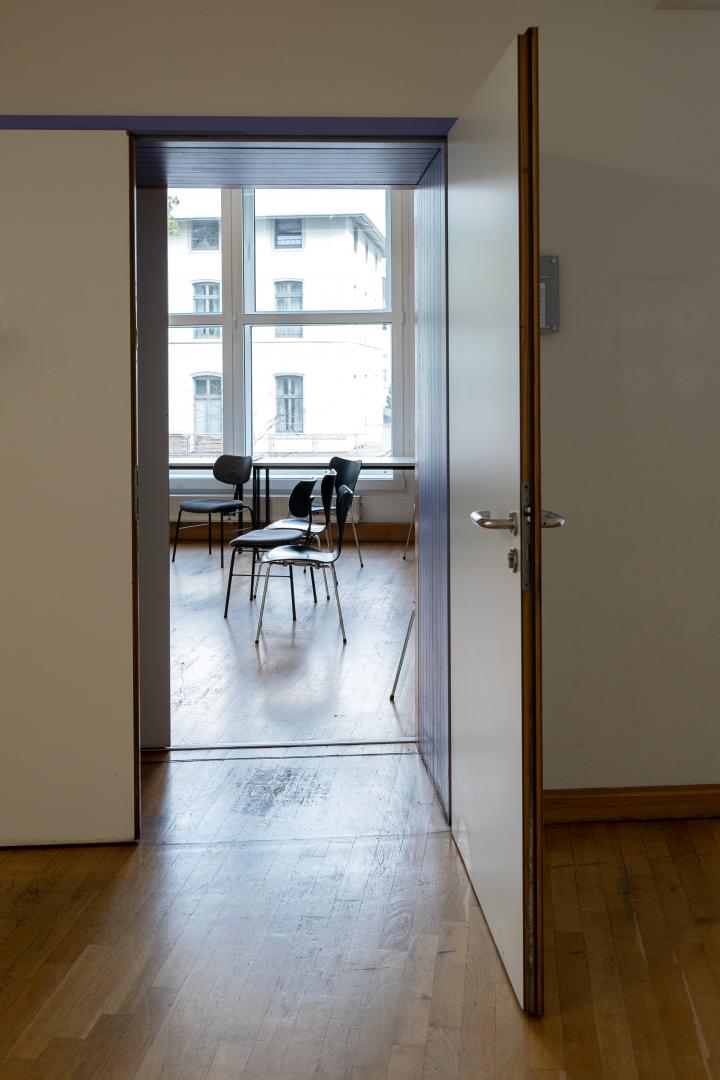 Blick durch die offene Tür eines Seminarraums der HfMDK auf mehrere Stühle.