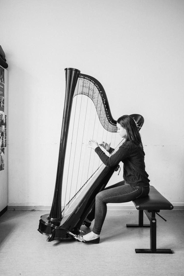 Eine Harfenistin beim Üben im Proberaum