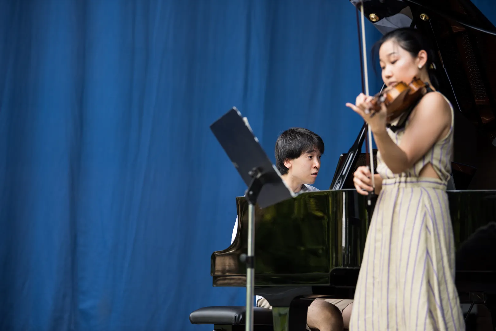 Ein Pianist und eine Geigerin vor einem blauen Hintergrund