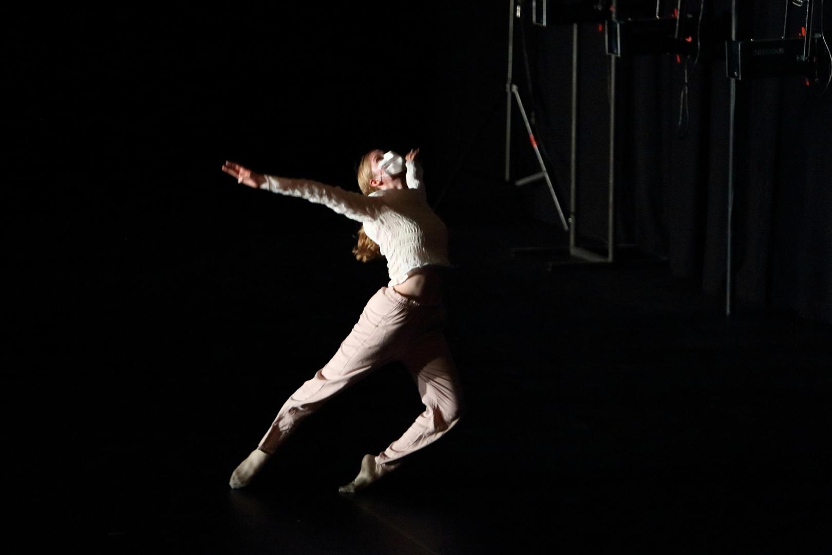 Eine Tänzerin im Sprung, die Arme weit ausgebreitet.