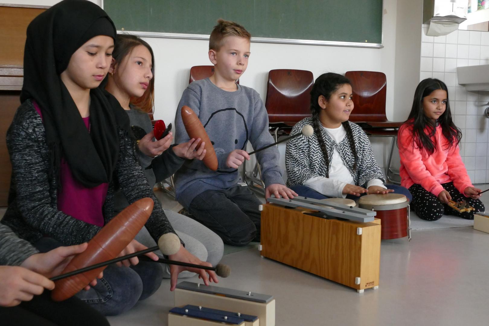 Eine Gruppe Schülerinnen und Schüler mit Musikinstrumenten im Klassenraum.