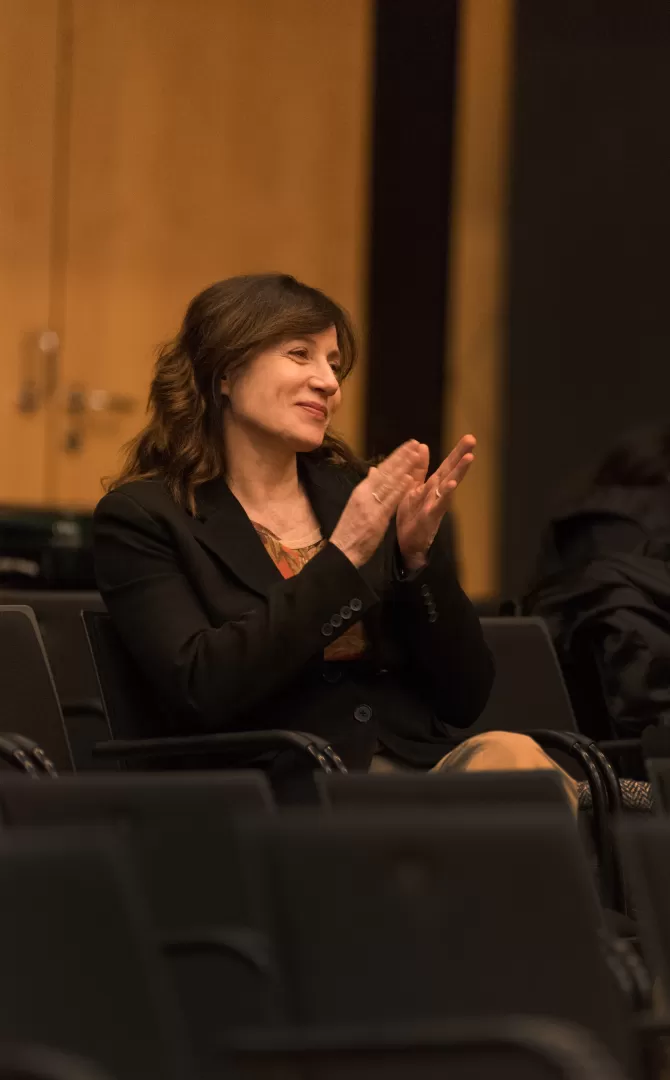 Die Komponistin Lucia Ronchetti sitzt lächelnd und klatschend im Zuschauerraum