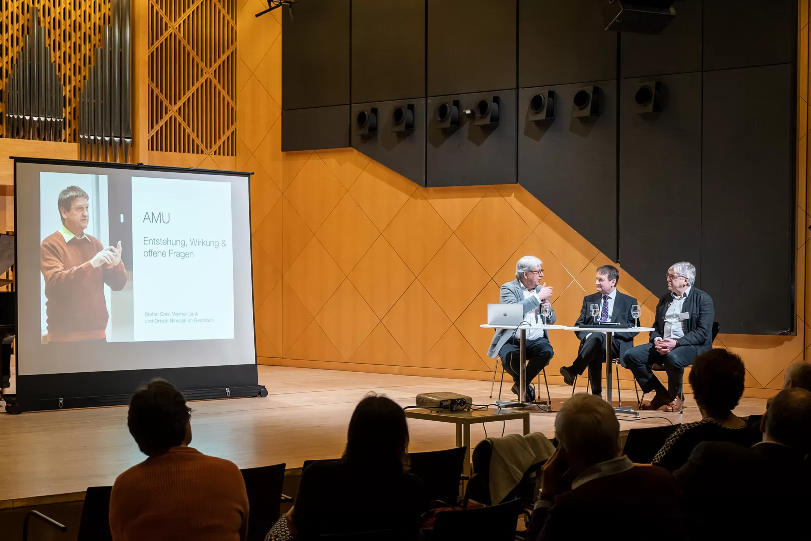 Stefan Gies, Werner Jank und Ortwin Nimczik im Gespräch an einem Tisch auf der Bühne