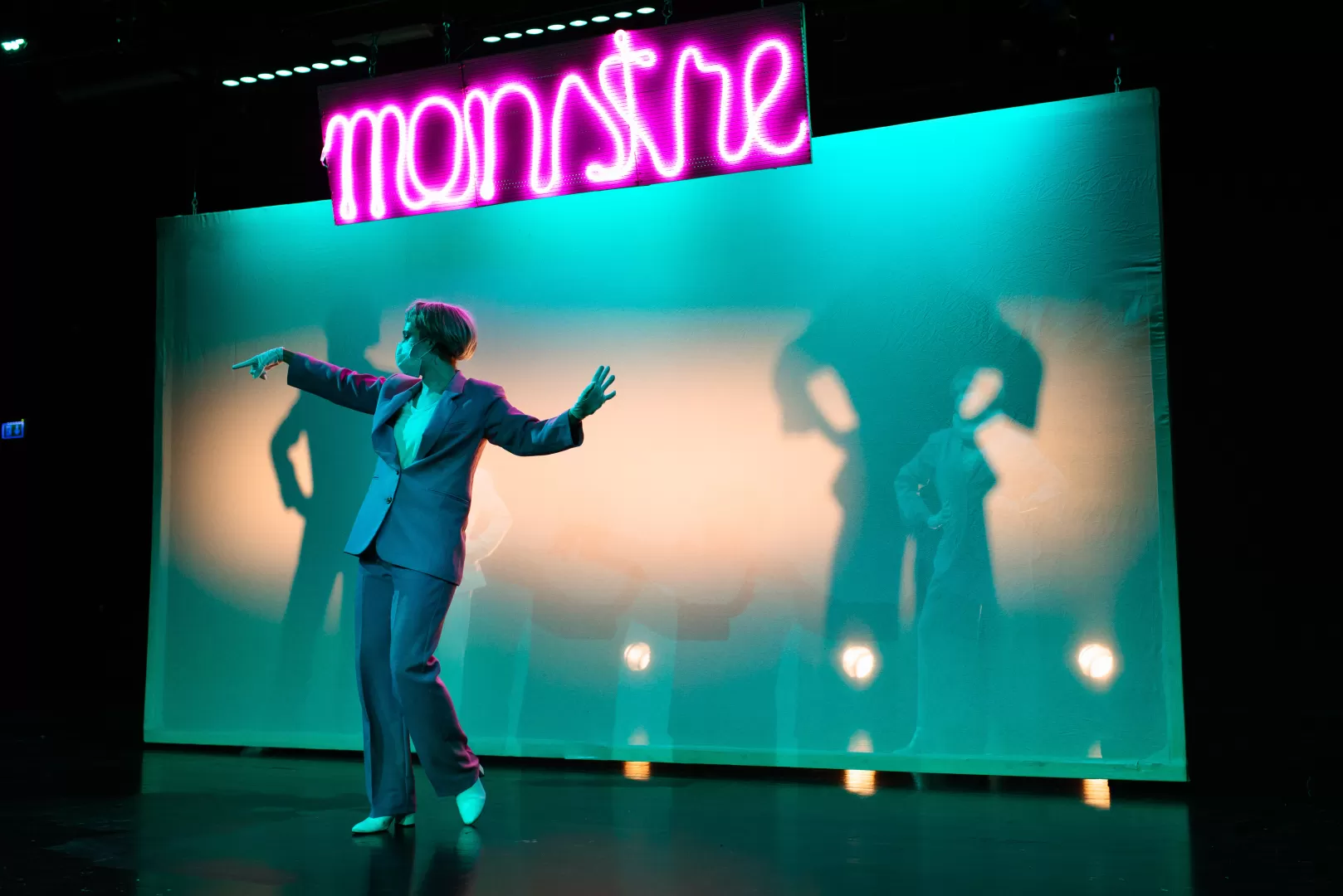 Schauspielerin vor Schattenwand in tänzerischer Bewegung.