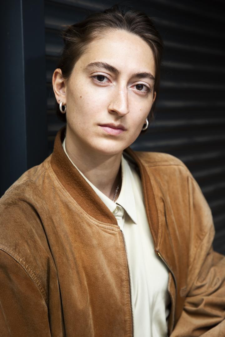 Portrait der Studierenden in brauner Jacke, frontal.