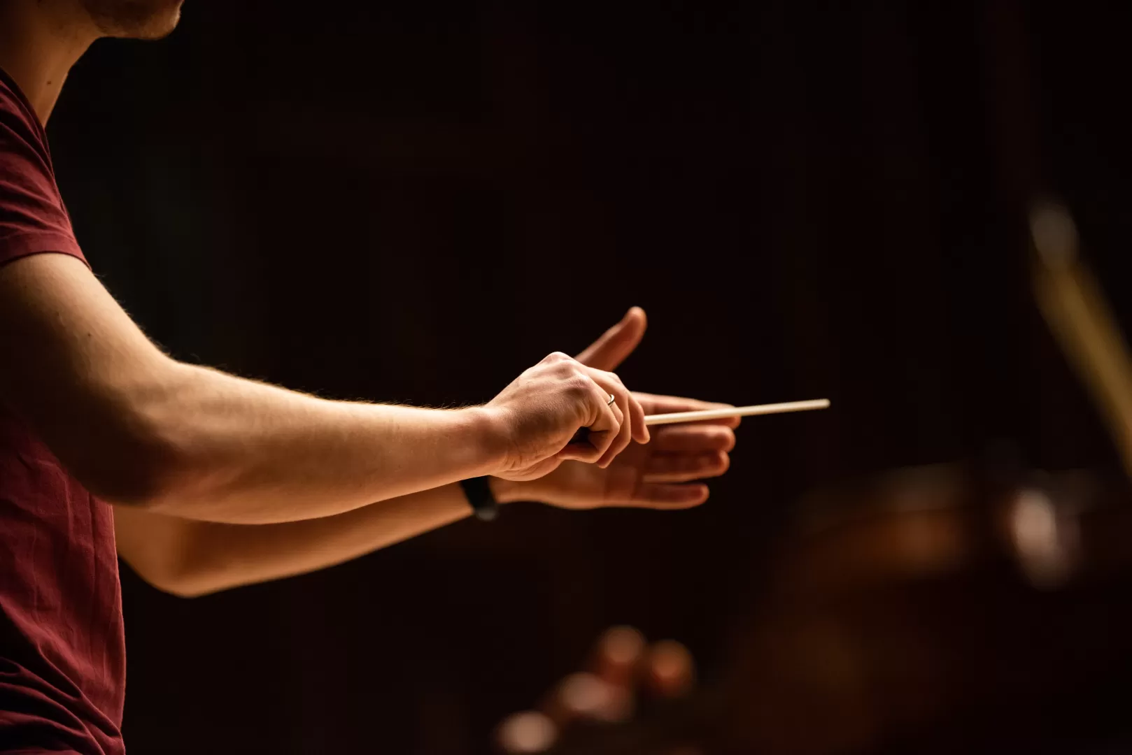 Nahaufnahme der Hände eines Dirigenten mit Taktstock.