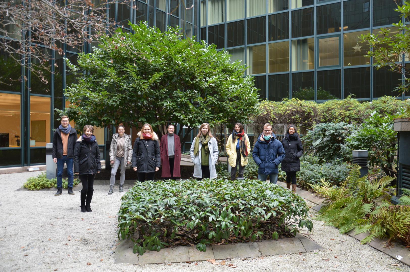 Gruppenfoto der neun Studierenden aus dem Jahrgang 22, in zwei Reihen vor einem Baum im Innhof stehend 
