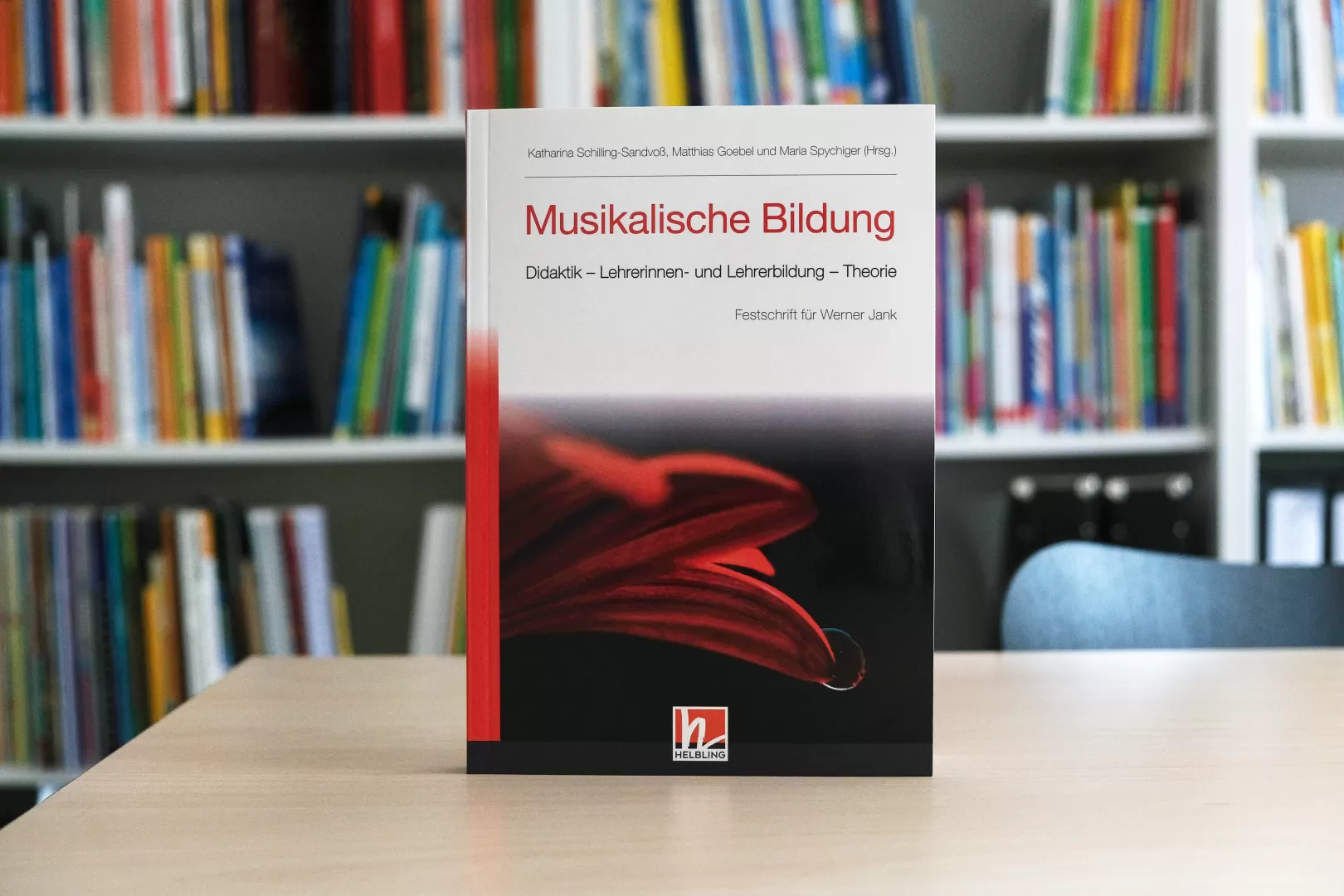 Das Buch mit dem Titel "Musikalische Bildung. Didaktik - Lehrerinnen- und Lehrerbildung - Theorie" steht auf einem Tisch, im Hintergrund ein Bücherregal.
