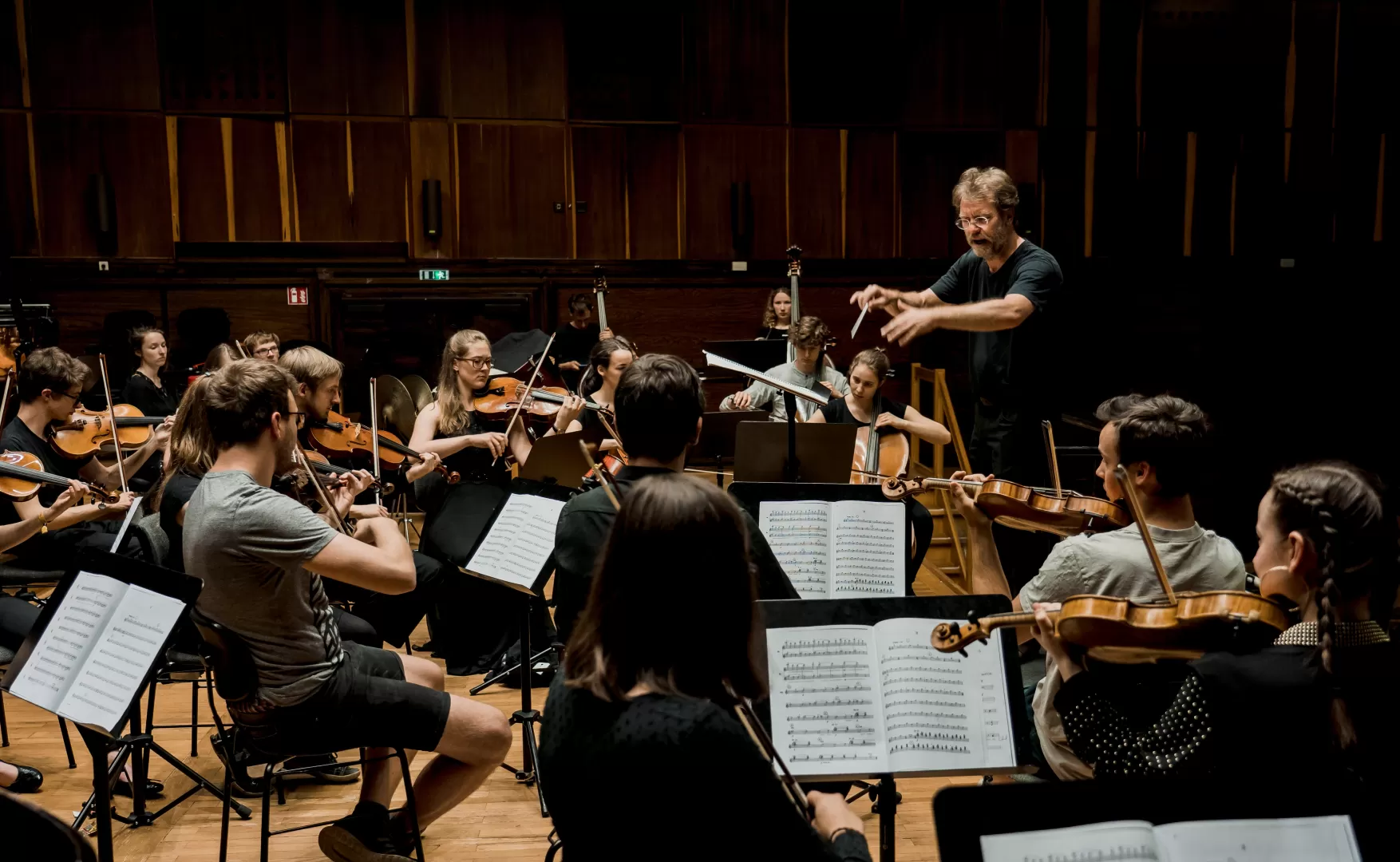 Probe des Collegium Musicum (Orchester der Lehramtsstudierenden), Musiker*innen und Dirigent auf der Bühne.