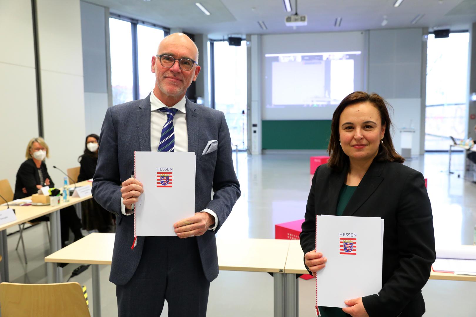 Elmar Fulda (Präsident der HfMDK) und Ayse Asar (Staatssekretärin im Hessischen Ministerium für Wissenschaft und Kunst) halten die unterzeichneten Zielvereinbarungen in die Kamera