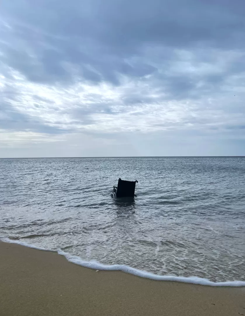 Am Strand von Mallorca treibt ein leerer Rollstuhl in der Brandung.