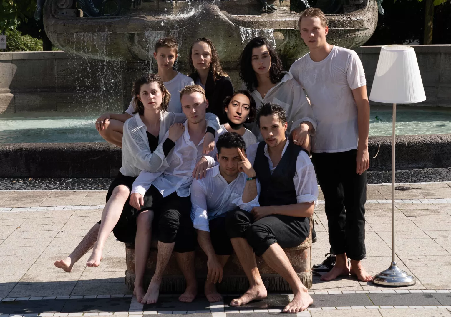 Gruppenfoto mit neun Absolvierenden vor einem Brunne, alle sind nass.