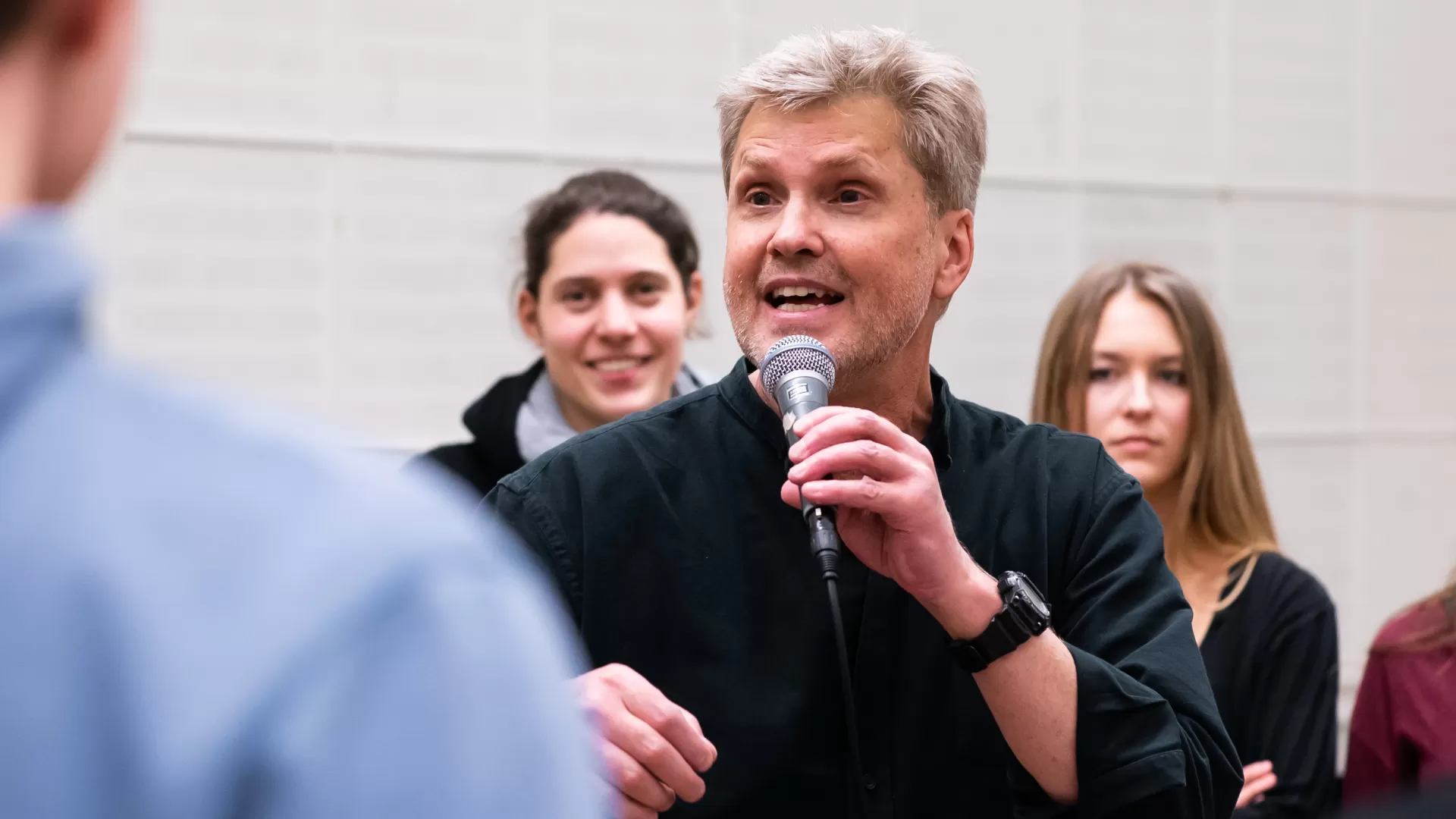Roger Treece in einem Workshop, in der linken Hand hält er ein Mikrofon.