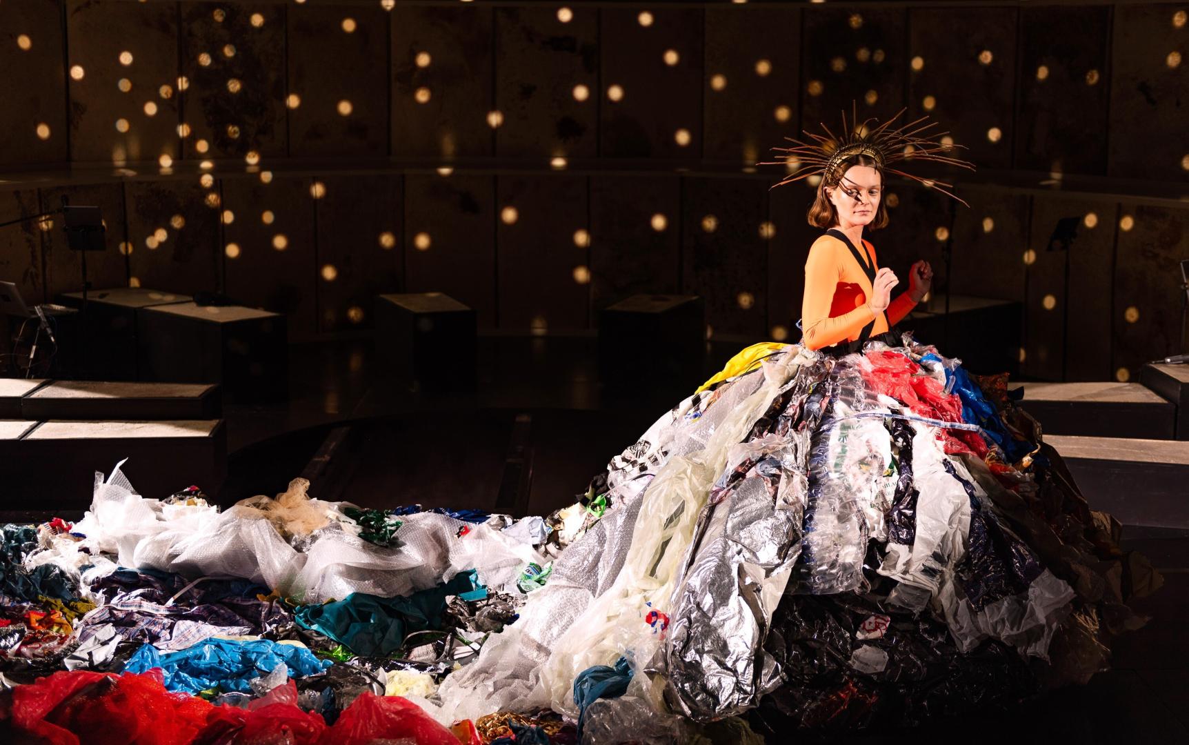 Schauspielerin in einem großen Gewand aus Müll.