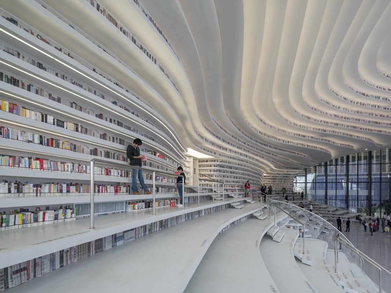 Lesesaal der Tianjin Binhai Library: Weiße wellenförmige Bücherregale und Stufen.