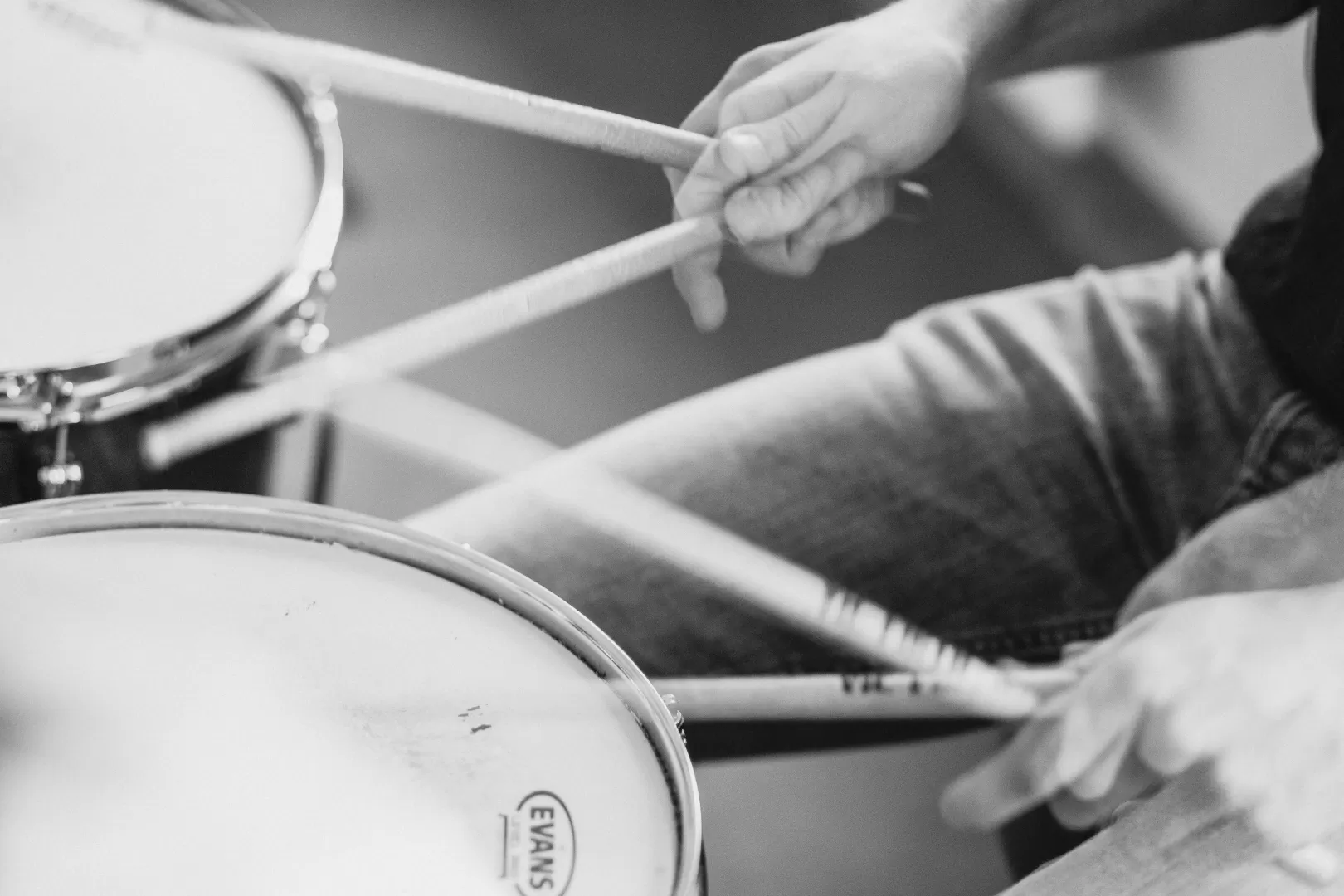 Schwarz-weiß Nahaufnahme der Hände eines Schlagzeugers beim Spiel auf dem Instrument.