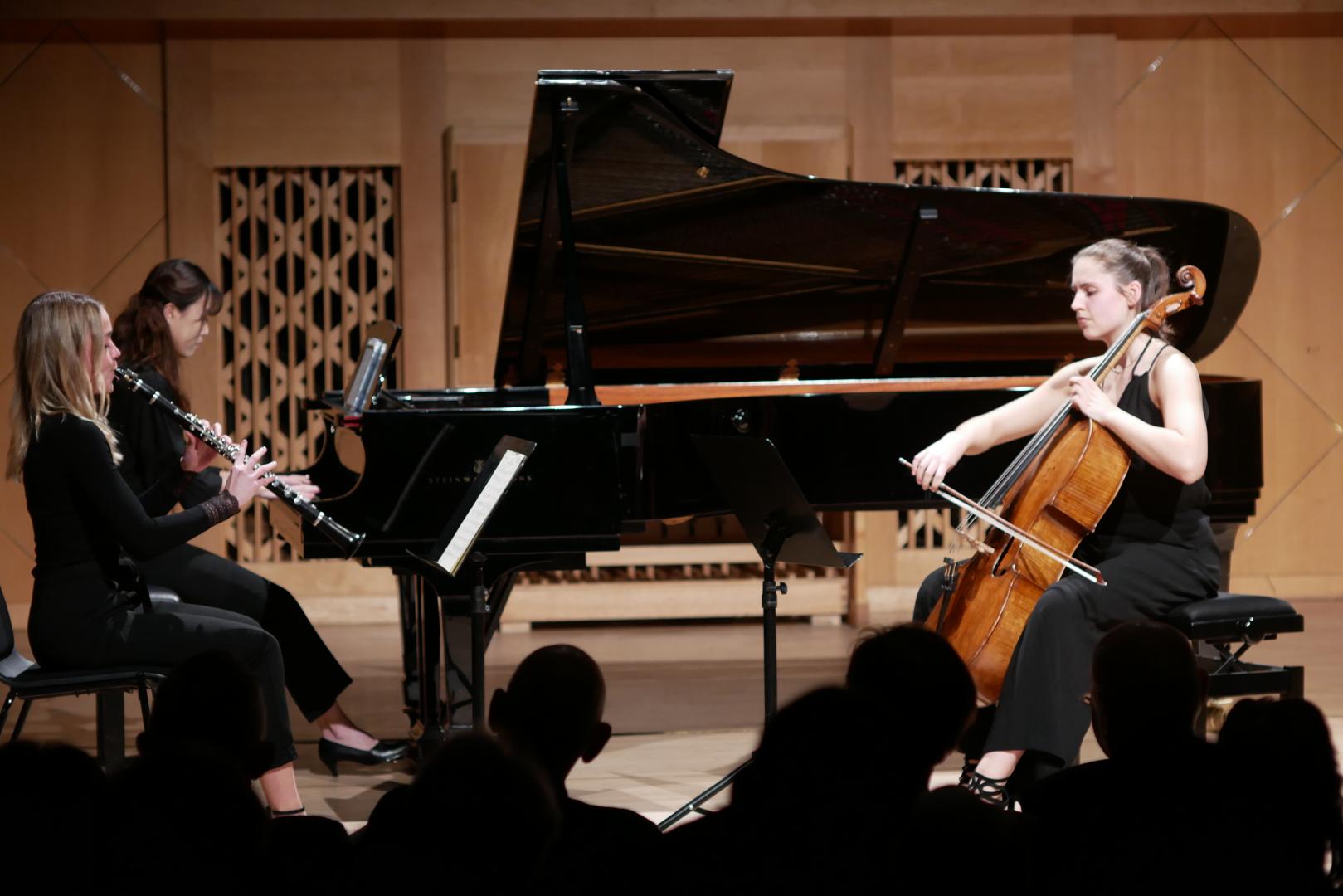 Eine Klarinettistin, eine Pianistin und eine Cellistin spielen zusammen vor Publikum.