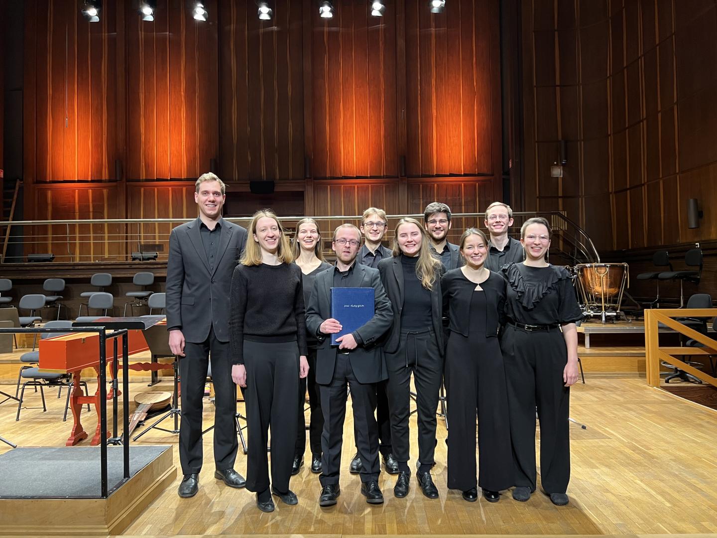 Alle Dirigent*innen des zweiten Konzerts im Gruppenfoto, ein Student hält die Partitur