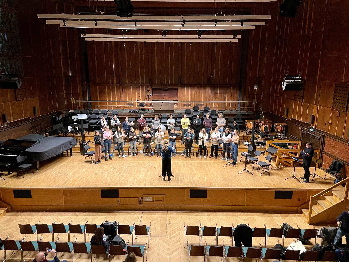 Der Kammerchor probt auf der Bühne, Barney von Voces8 schaut zu