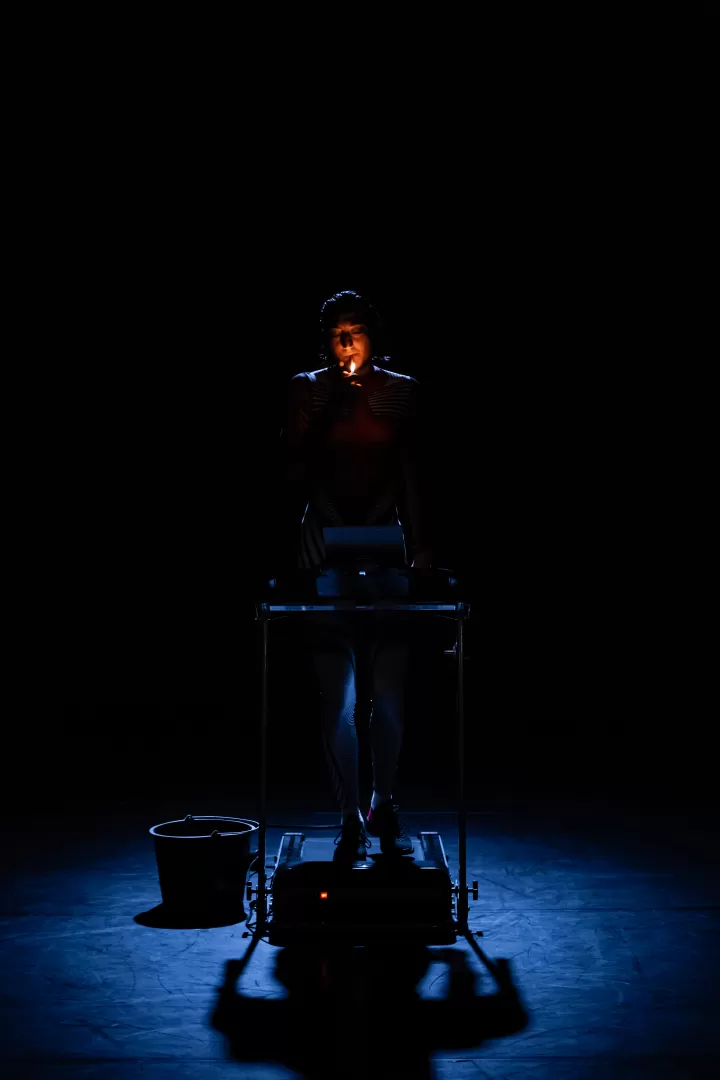 Schauspielerin auf einem Laufband zündet sich eine Zigarette an.