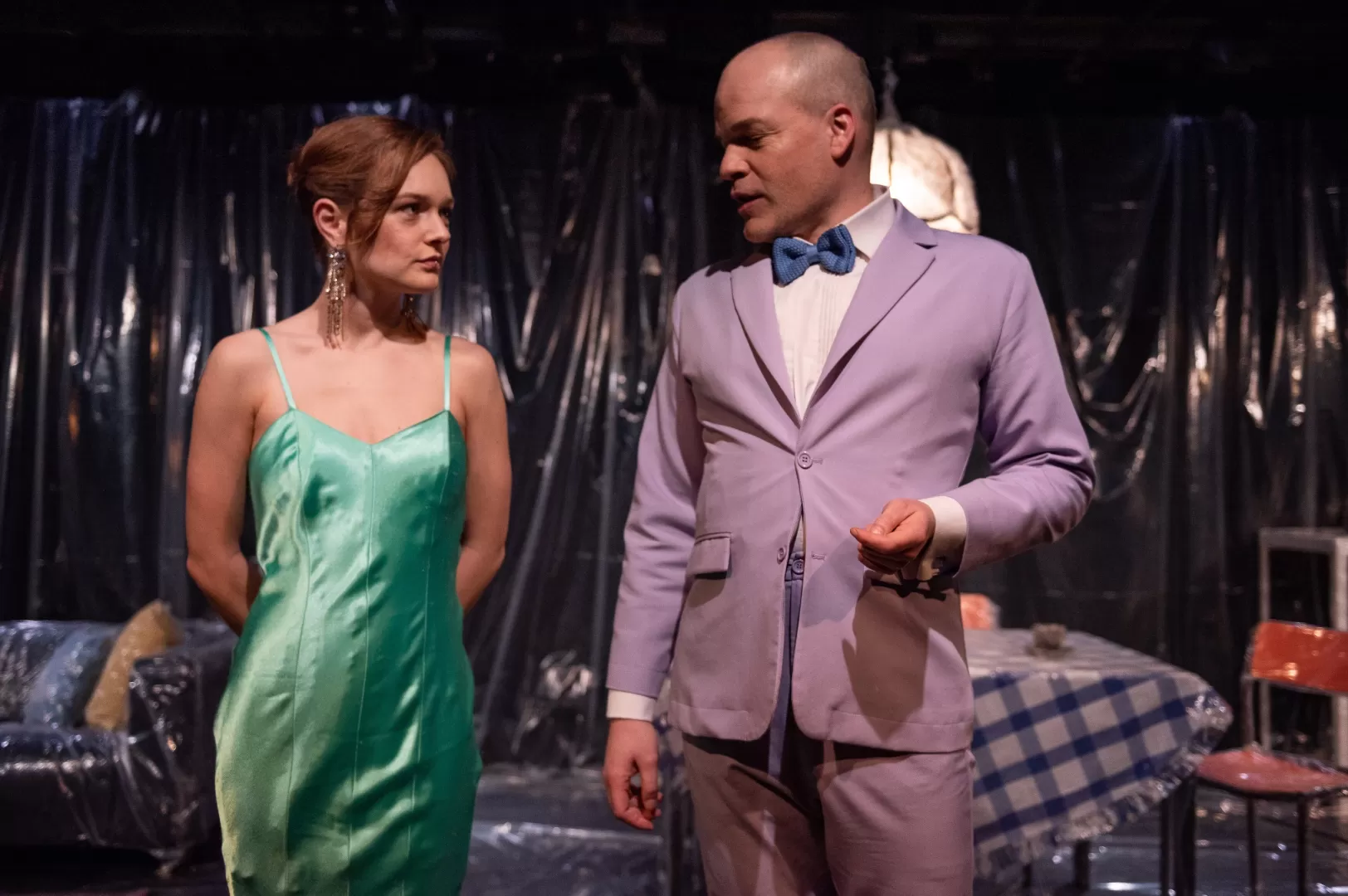 Eine Frau und ein Mann, beide elegant gekleidet, stehen nebeneinander, sich zugewandt.