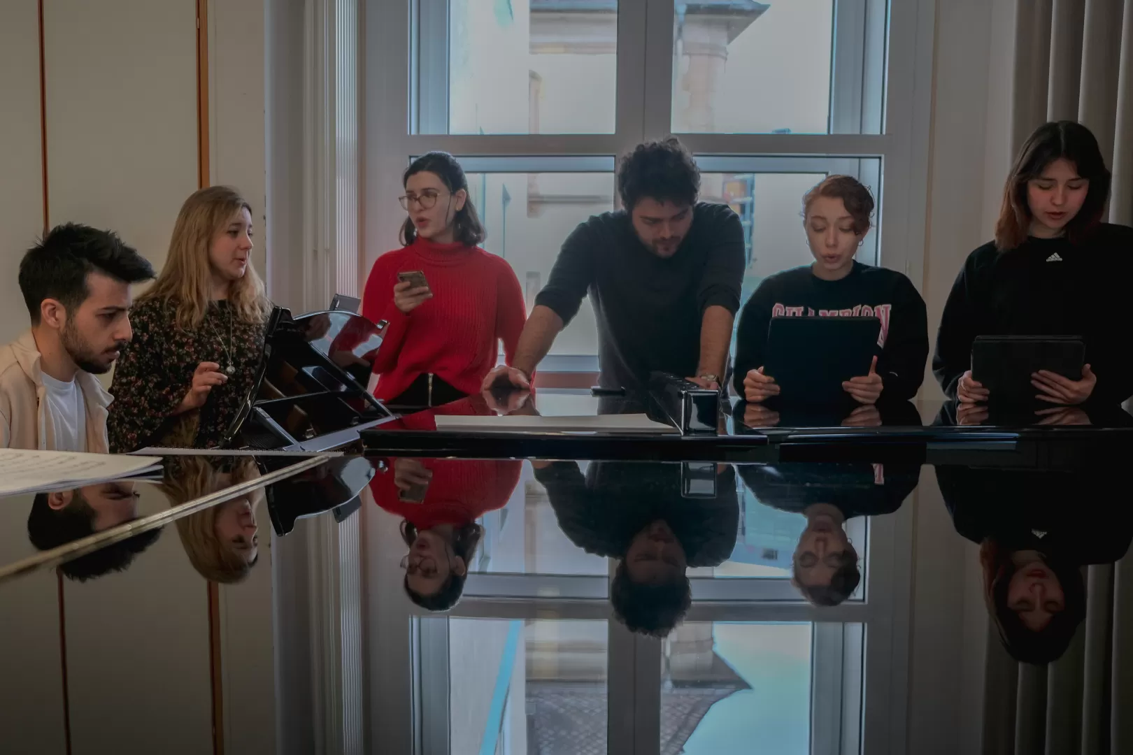 Probe, bei der 6 Musiker*innen singend um einen Flügel herum stehen.