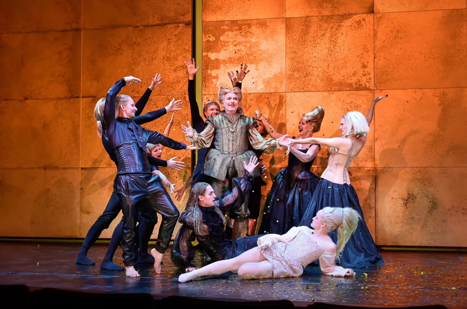 Eine Gruppe Personen, die alle auf einen in der Mitte stehenden Mann zeigen.