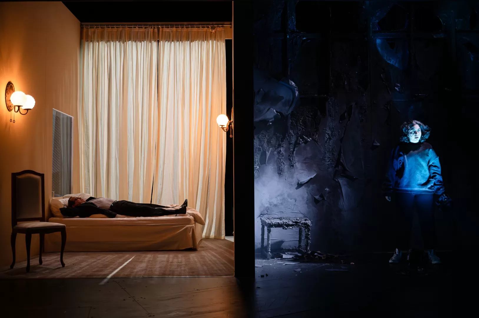 Zweigeteilter Bühnenraum. Links ein Hotelzimmer, rechts ein dunkler Raum.