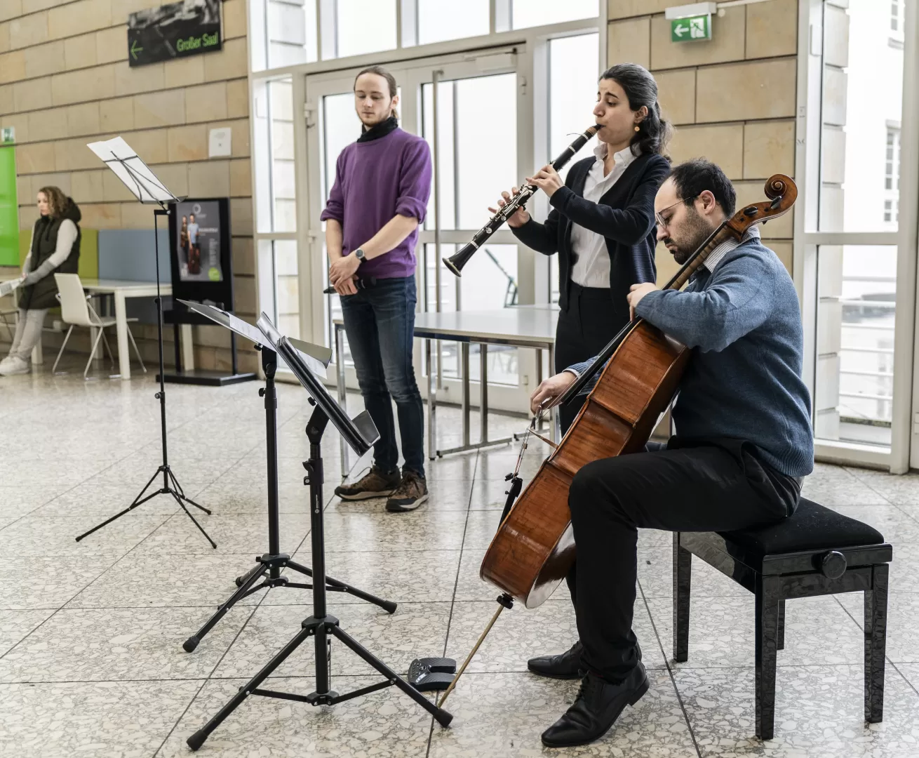 Zwei Musiker*innen und ein Sprecher im Foyer der HfMDK.