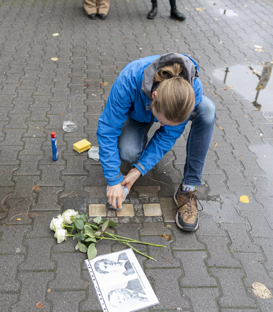 Friedrick Brückner putzt die drei Stolpersteine vor dem HfMDK-Gebäude