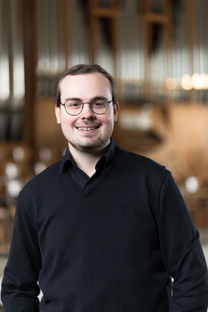 Lukas Euler mit verschwommener Orgel im Hintergrund