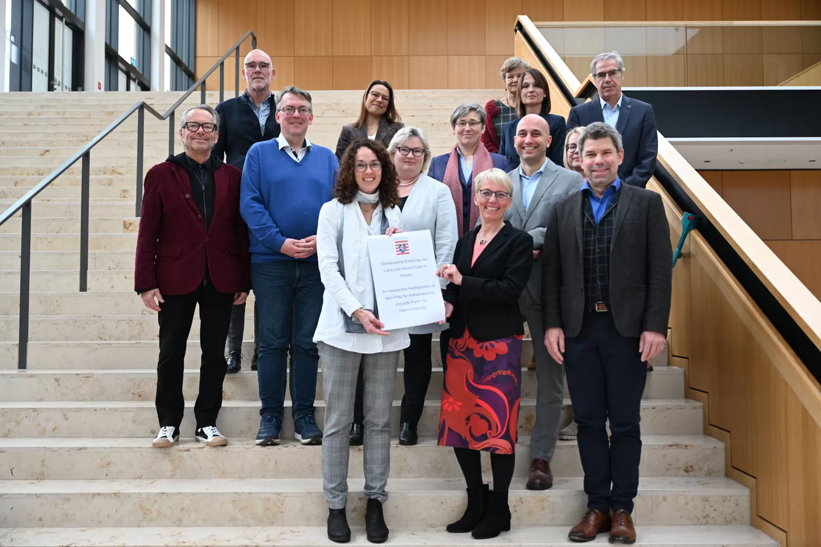 Die hessischen Hochschulleiter*innen gemeinsam mit Wissenschaftsministerin Angela Dorn auf Treppenstufen.