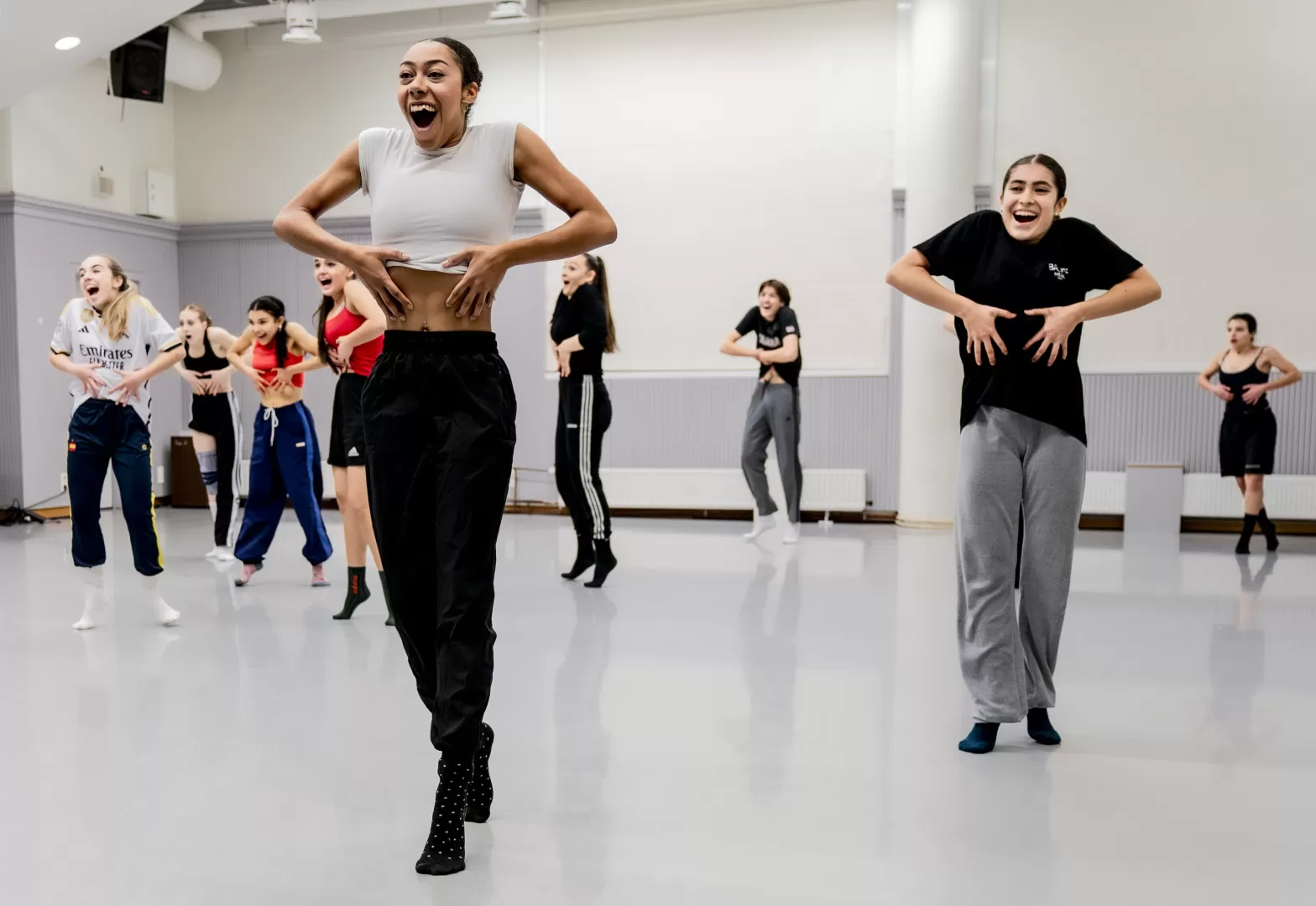 Eine Gruppe von Tänzer*innen, die im Raum verteilt stehen.