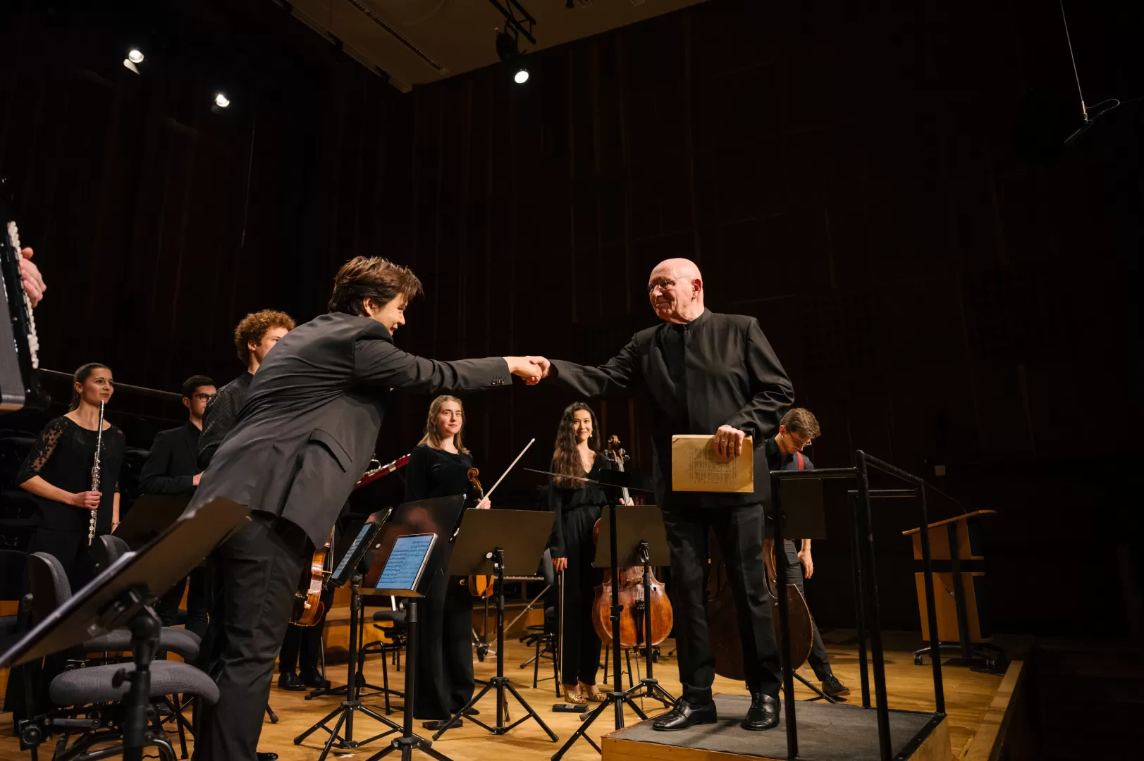 Christoph Eschenbach gibt dem ersten Geiger des Studierendenensembles die Hand