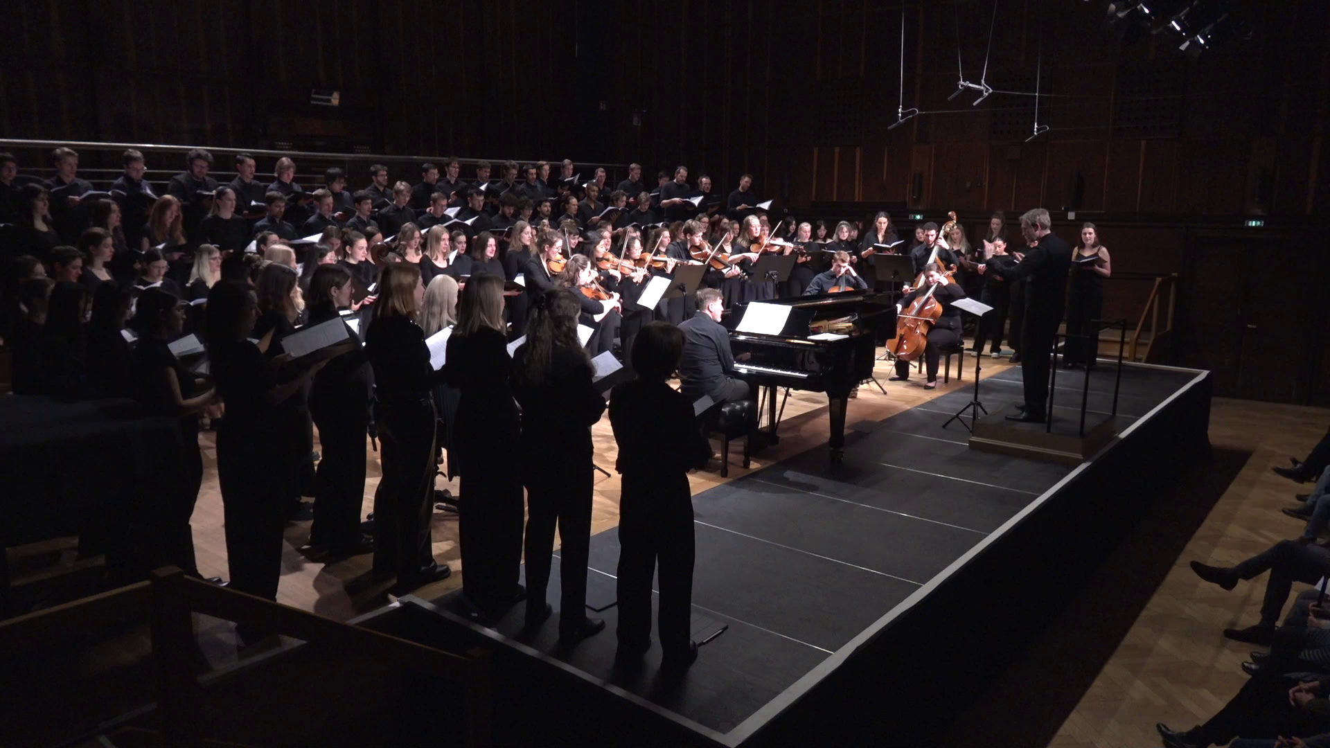Blick auf Bühne: Florian Lohmann dirigiert Streicherensemble und großen Chor