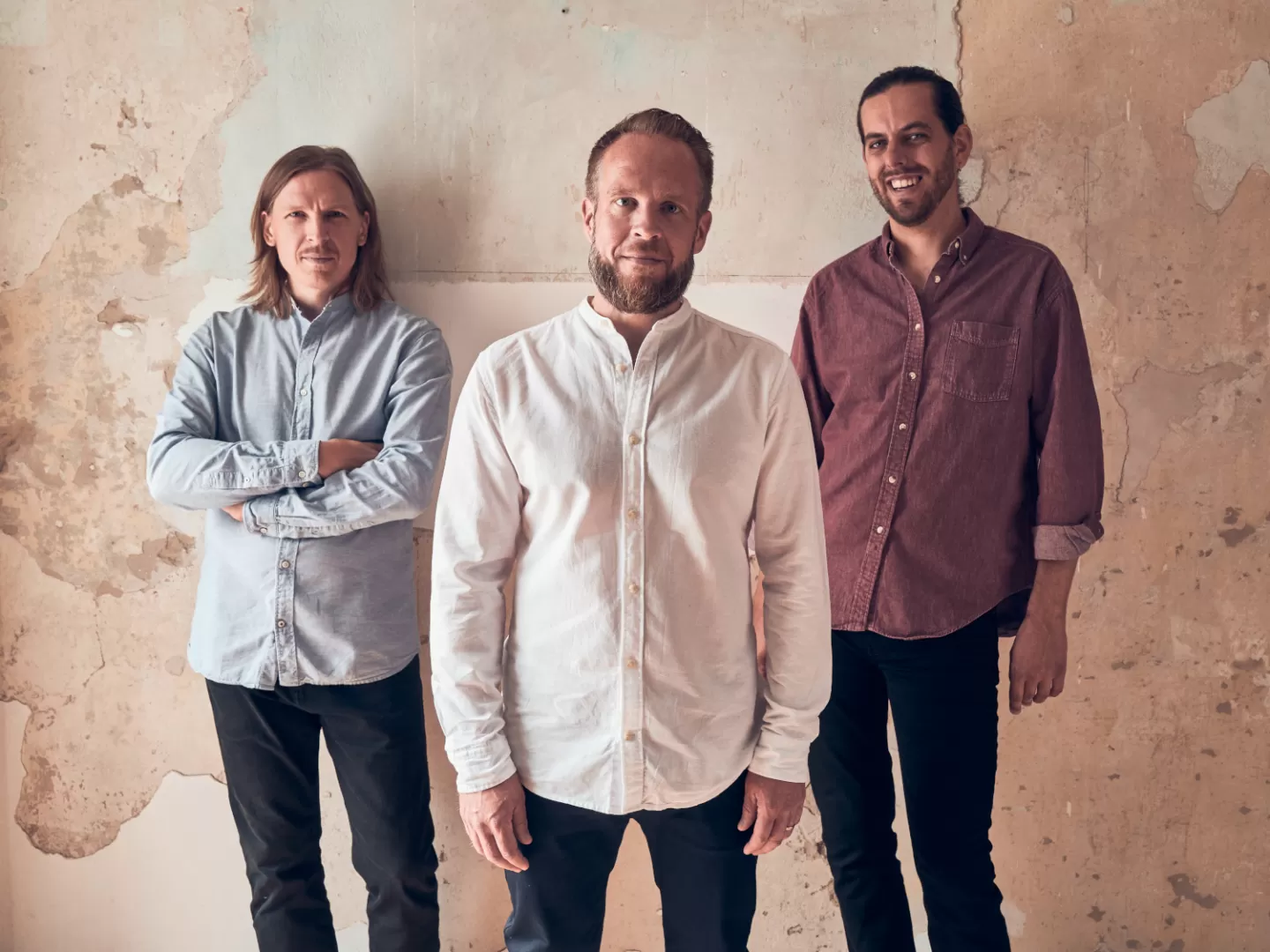 Die drei Musiker des Emil Brandquist Trios stehen vor einer rosa Wand.