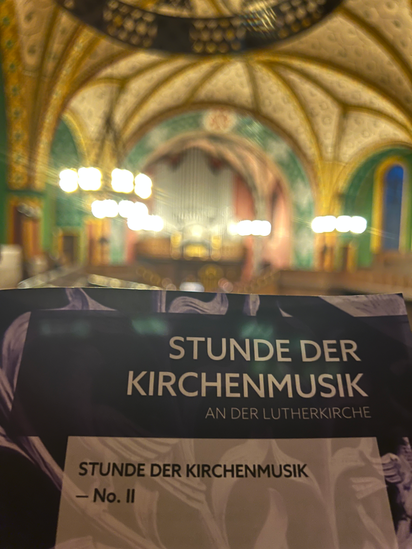 Programm der "Stunde der Kirchenmusik" mit bunter Kirche im Hintergrund