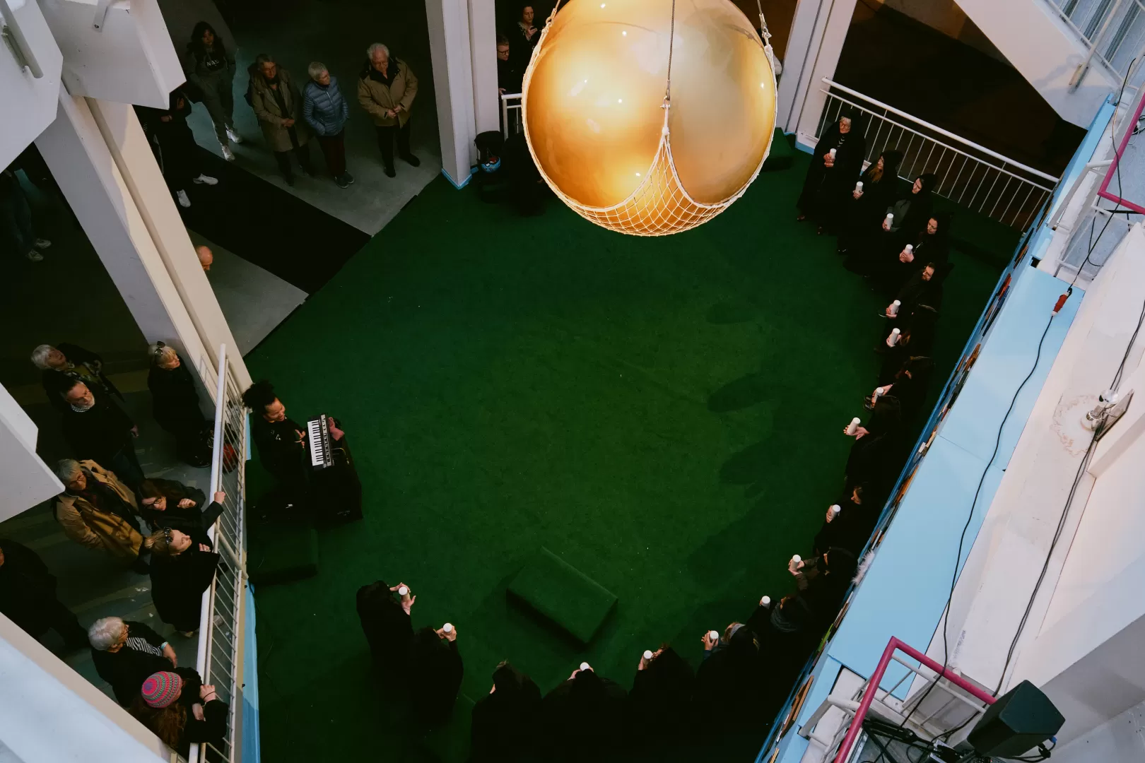 Die Goldene Kugel hängt über den in schwarzen Kutten gekleideten Mitwirkenden.