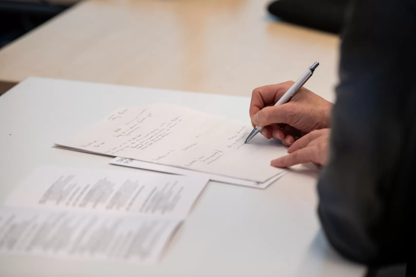 Eine Hand schreibt mit einem Kuli auf Papier.