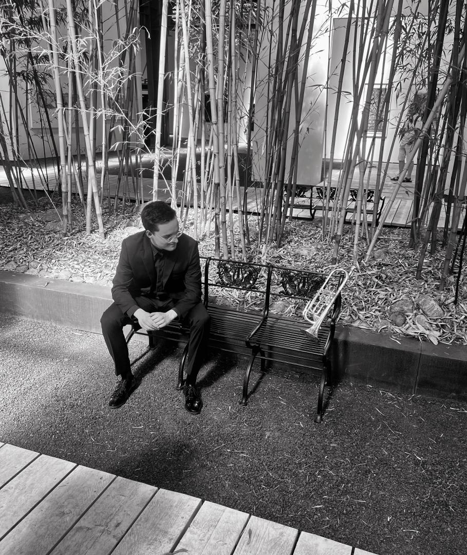 Sebastian Kellner sitzt auf einer Bank und schaut seine Tompete an, die ebenfalls auf der Bank liegt