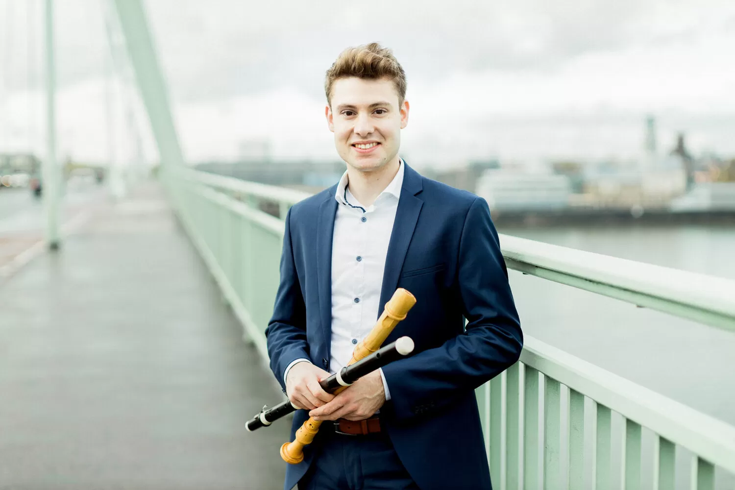 Sebastian Schmidt steht auf einer Brücke, in der Hand hält er eine Blockflöte und eine Traversflöte.