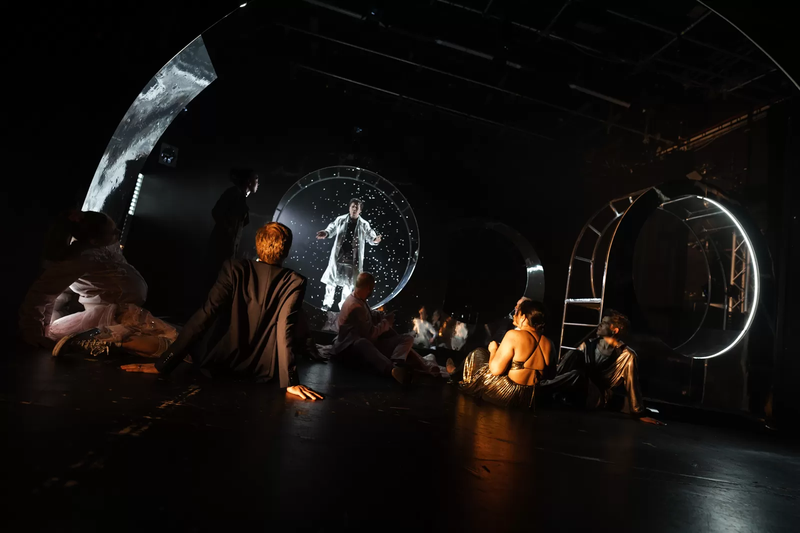 Eine Gruppe sitzt auf dem Boden und schaut zu einem Mann, der Konfetti wirft.