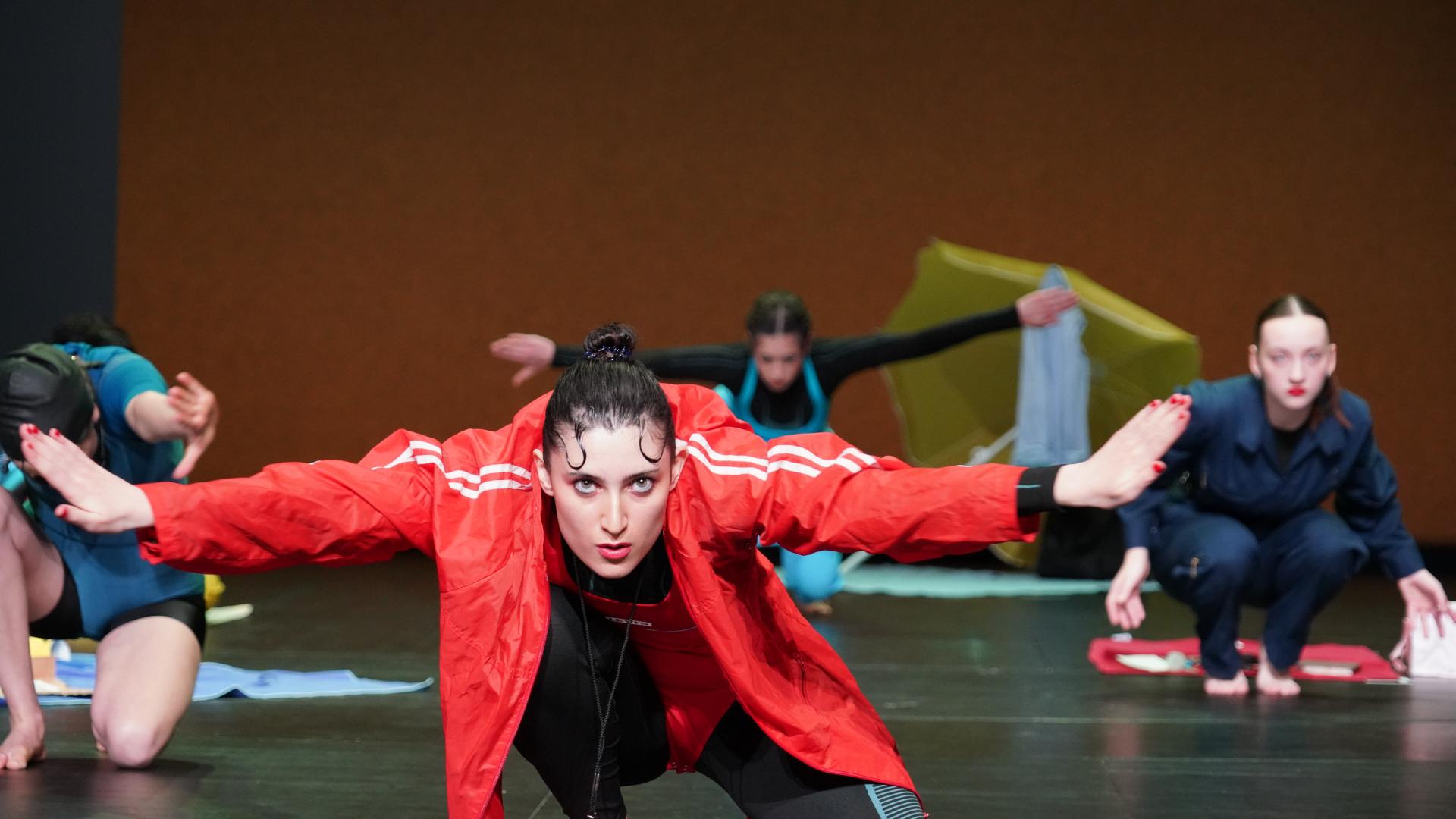 Performerin in roter Trainingsjacke mit ausgebreiteten Armen