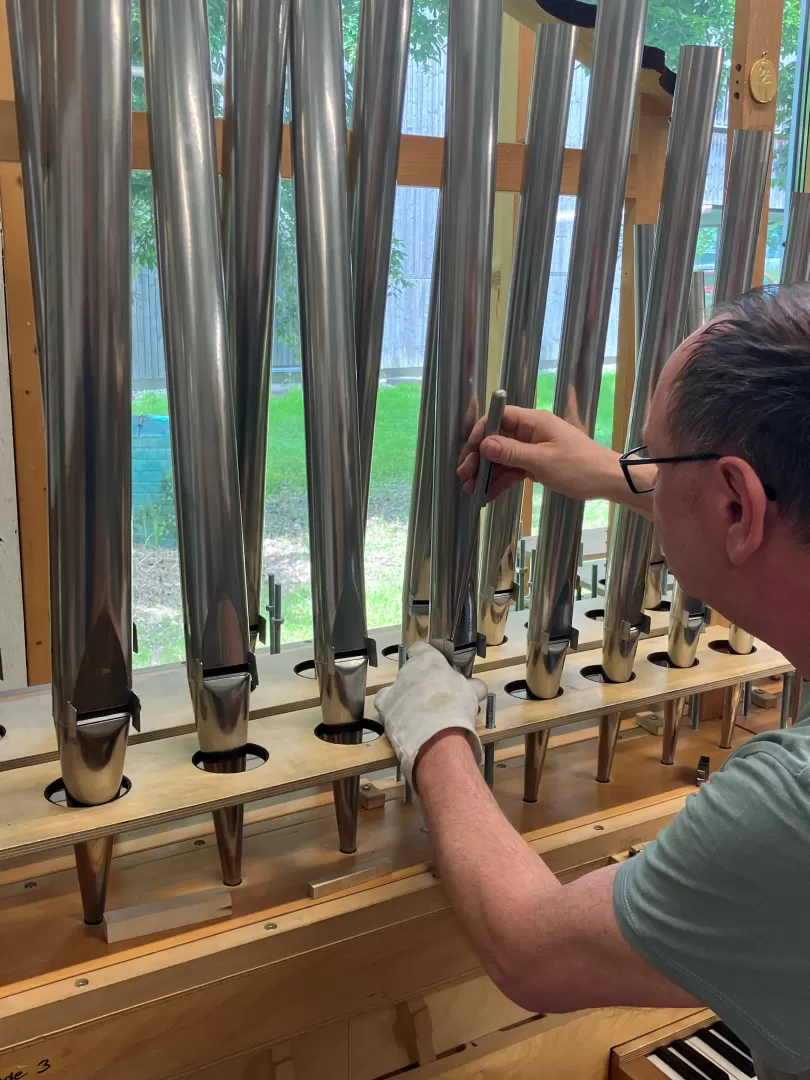 Ein Mitarbeiter bei der Vorintonation der Pfeifen. Er trägt einen Handschuh an der linken Hand und steckt einen Stab in den Aufschnitt einer Pfeife.